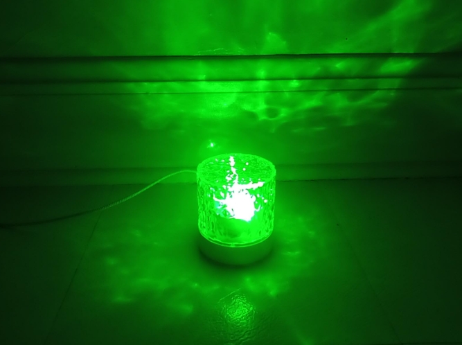 The Bizggco Water Ripple Lamp is a decent product that I recently had the chance to try out. Its small, compact size and lightweight build make it portable and easy to move around.

Crafted from clear acrylic, this projector stands sturdy. The minimalist design is simple and satisfying.
With low to moderate brightness, the projector isn't flashy or annoying. It causes a watery pattern to swirl around the walls, although it doesn't project very far.

The limited lighting area does have an intimate charm. The rechargeable battery is nice, but I just plug it in and leave it charged. Equipped with a remote control, the Bizggco projector produces several different colors and can also project a multi-color mix. However, I still can't quite figure out where the buttons are located on the lamp itself.

I've sampled several of these sorts of projectors and can say this product is pretty good. It is certainly reliable. The subtle, soothing display would make a perfect night light.